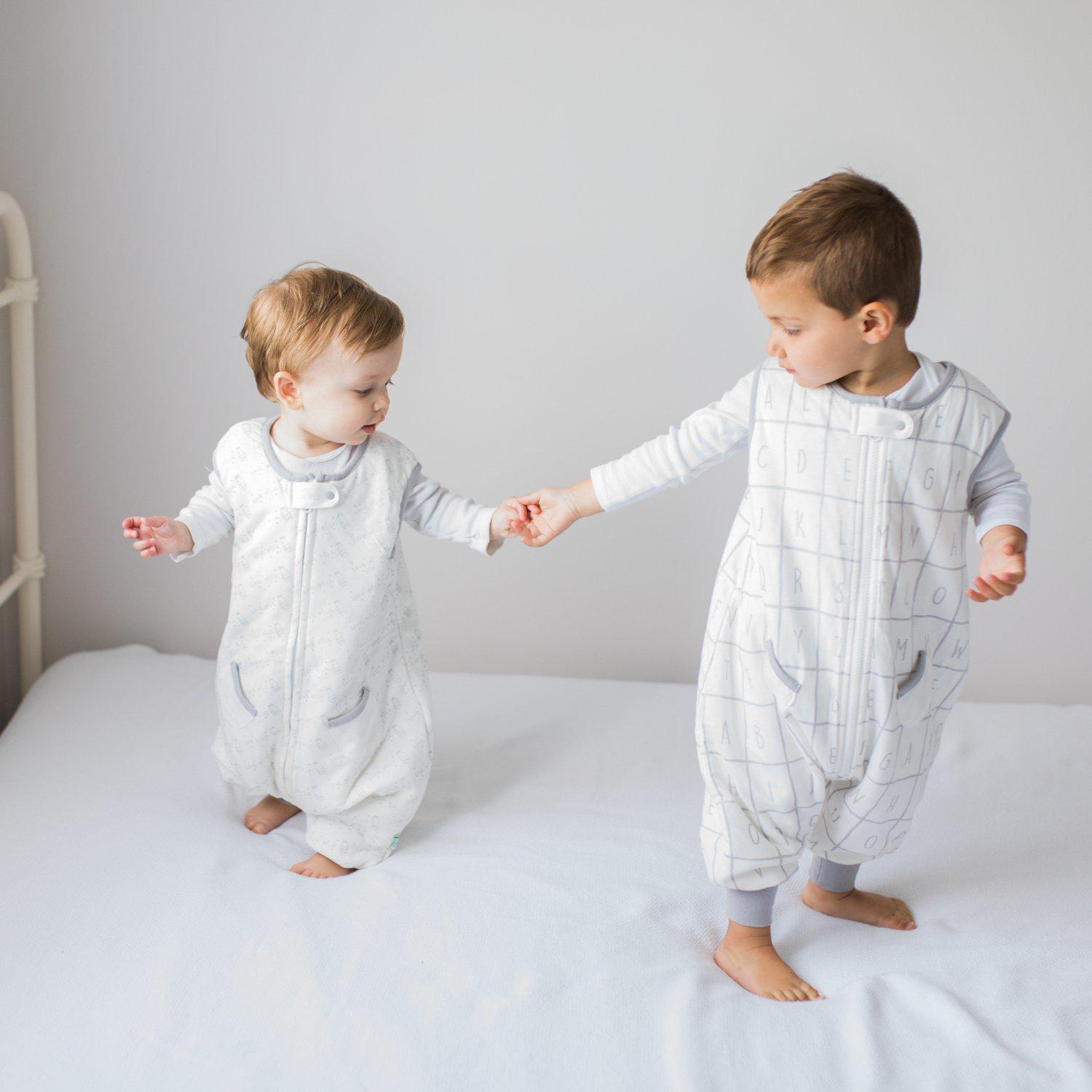 Two toddlers holding hands wearing Tealbee Dreamsuit in different TOG and Design