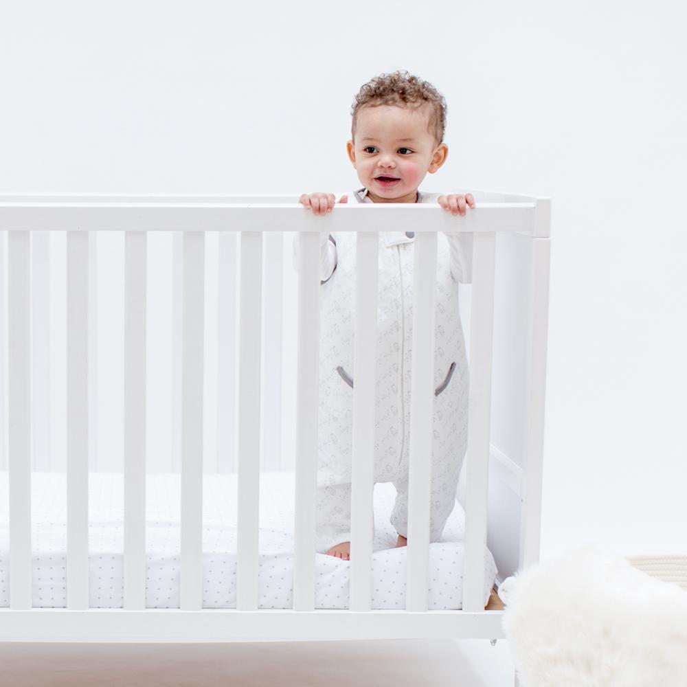 Toddler in a crib wearing Tealbee Love Milk Dreamsuit and Toddler Sleep Sack with legs